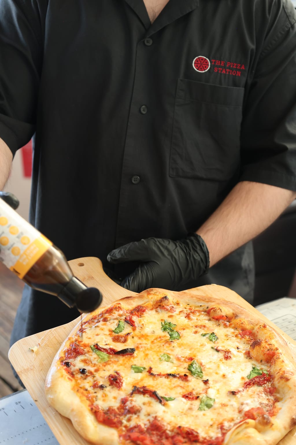 Pizzaiolo slicing a Margherita on a wooden peel — live catering at a GTA event