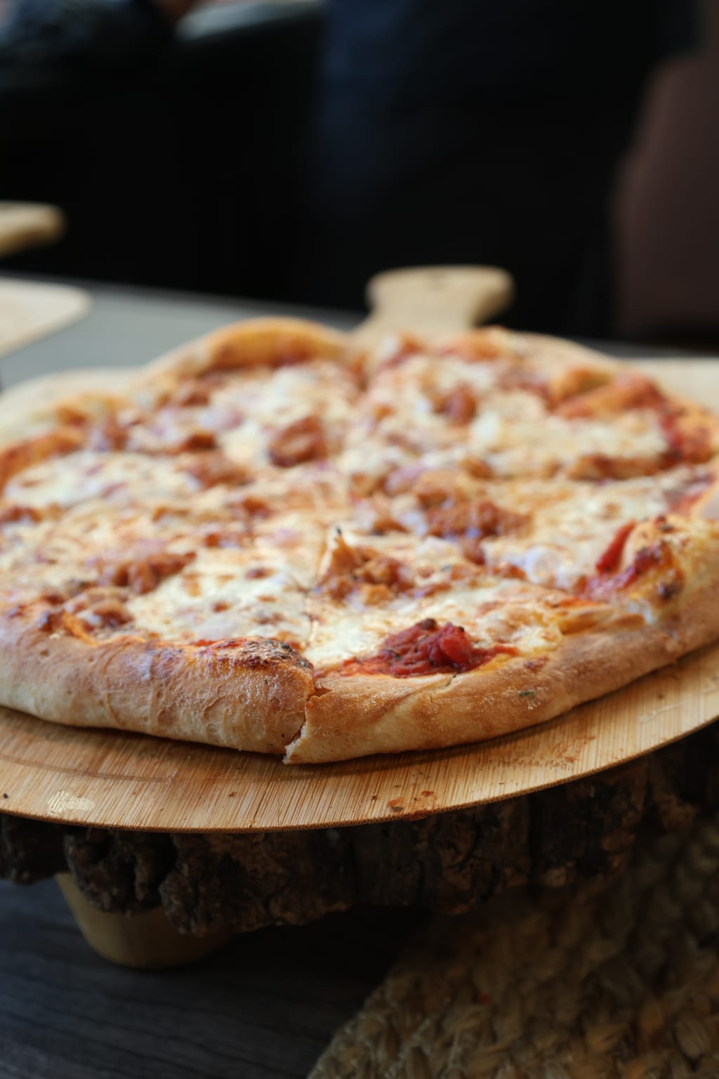 Finished Margherita pizza on a wooden board next to The Pizza Station branded card