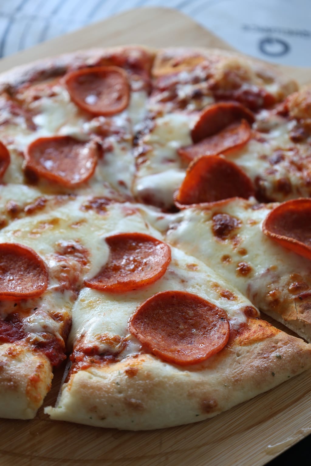 Hand-stretched pepperoni pizza fresh from the oven — blistered crust, pooled cheese, at a GTA event